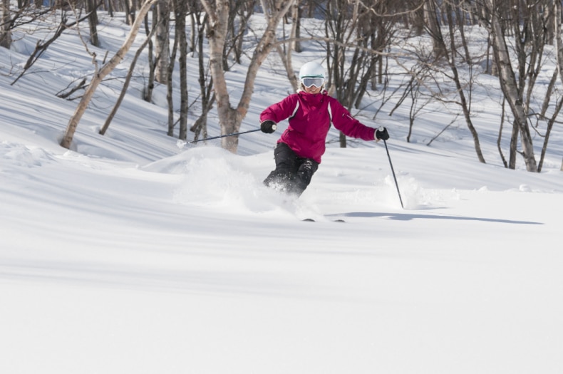 Female skier in maroon on fresh powder at Myoko Kogen Ski Resort in Japan