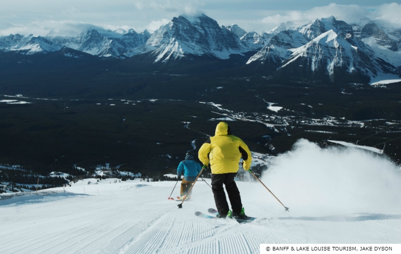 Skier in yellow and a skier in blue descend one of the many runs at Lake Louise Ski Resort in Canada's Rocky Mountains