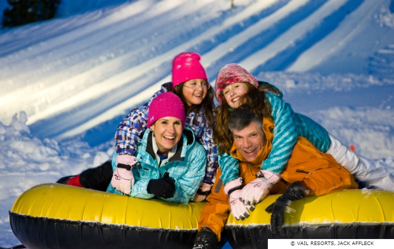 Happy family at the end of a ride in an inflatable at a snow field