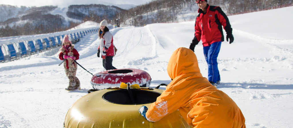 Mum and Dad waiting at the bottom of the snow tubing run for their kids